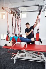 Rehabilitation specialist doing active treatment on suspension straps to elderly patient....
