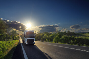 Landscape with a moving truck on the highway at sunset