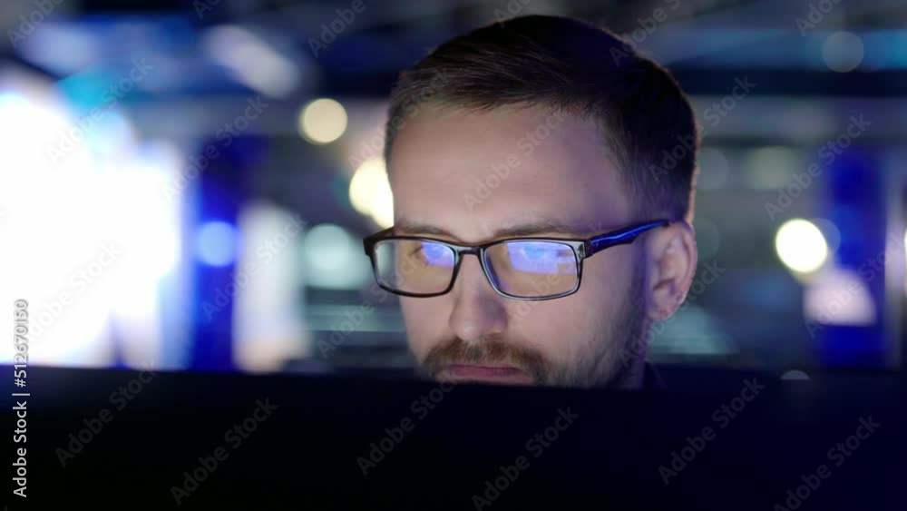 Wall mural close up view of a focused man with glasses in front of a computer.
