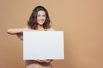 woman on a beige background smiles and holds a white sign in her hands. an advertising poster about...