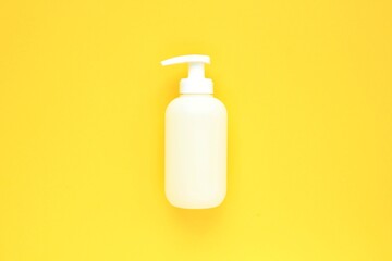 White unbranded plastic dispenser pump bottle on yellow background with copy space for text. Cosmetic package mockup, liquid soap flacon, hand sanitizer without label, shampoo organic spa, shower gel