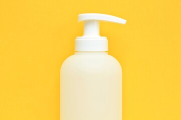 White unbranded plastic dispenser pump bottle on yellow background with copy space for text. Cosmetic package mockup, liquid soap flacon, hand sanitizer without label, shampoo organic spa, shower gel