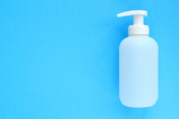 White unbranded plastic dispenser pump bottle on blue background with copy space for text. Cosmetic packaging mockup, liquid soap flacon, hand sanitizer without label, shampoo organic spa, shower gel