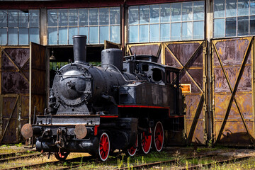 Naklejka premium A steam locomotive standing outside of historic locomotive shed. The shot was taken in natural lighting conditions