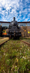 A steam locomotive standing outside of historic locomotive shed. The shot was taken in natural lighting conditions