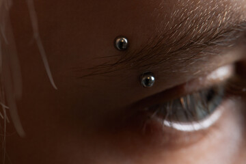 Professional placing the jewel of piercing on the temple on the head with ball. Tragus type.