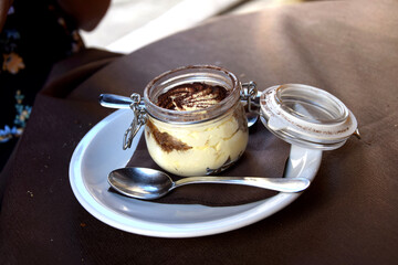 Italian tiramisu dessert in a glass jar, served in cafe - obrazy, fototapety, plakaty