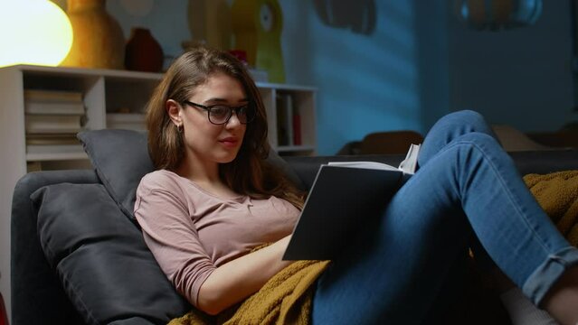 young woman relaxing at home reading book