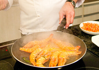 Shrimps being seasoned by the Chef and fried in the frying pan.
