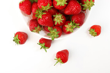 Red ripe strawberry in the white bowl, glossy background