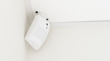 Modern white motion sensor on the wall in the room.