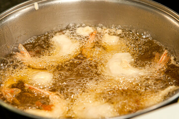 Shrimps being seasoned by the Chef and fried in the frying pan.
