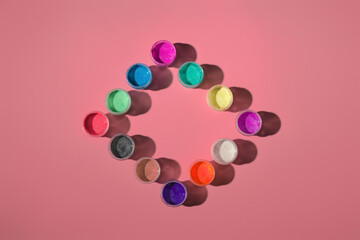 open jars with acrylic paint on a colored background, top view