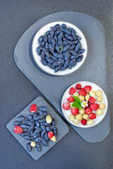 The first berries of the season, honeysuckle and strawberries are on the table. Selective focus, top view