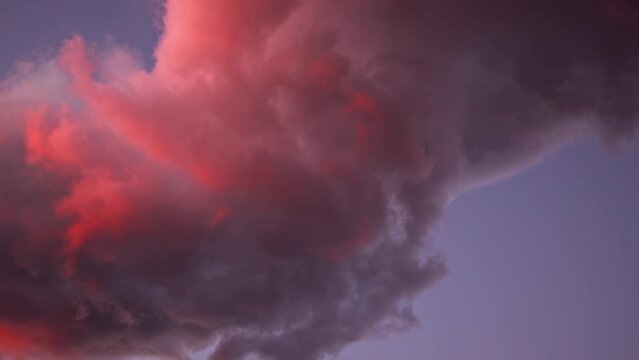 Colorful red lenticular clouds during sunset moving in the sky as they swirl.