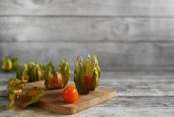 Ripe healthy physalis, over wooden board on a wooden background, copy space