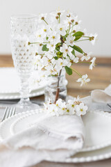 Rustic zero waste wedding decor with natural elements. Wooden table, candles, linen napkins, branches with green leaves. Eco-friendly decoration for the special dinner. Romantic and cozy place