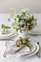 Fototapeta na wymiar Beautiful table decor for a wedding dinner with a spring blooming apple tree flowers. Celebration of a special event. Fancy white plates, wineglasses