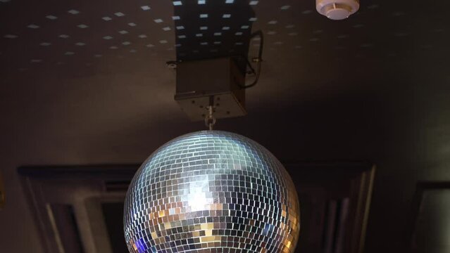 A rotating and sparkling disco ball on the ceiling in a dark room.