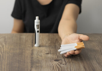 Woman with cigar in hand and vaper at table