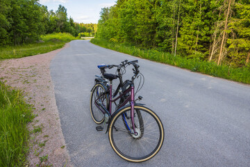 Fototapeta na wymiar Close up view of two bicycles isolated on asphalt road with forest landscape on background. Sweden. 
