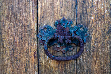 Stara ozdobna mosiężna kołatka na drewnianych drzwiach. 