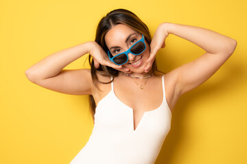 Naklejka premium Portrait of smiling brunette young woman with sunglasses isolated over yellow background.
