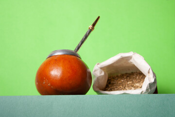 yerba and mate leaves in a paper bag on a green podium, selective focus