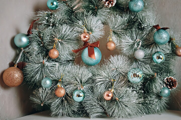 Traditional Christmas decorative wreath over grey marble wall. Holiday interior details. Round fir garland with snow, blue glitter balls and pine cones. New Year mood.