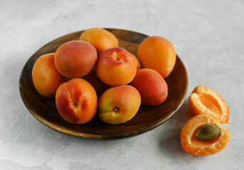 Fresh ripe apricots in a wooden bowl on a table made of natural marble.  Apricots are rich in vitamins and minerals, such as: vitamin A, beta-carotene, vitamin C, potassium, silicon, cobalt