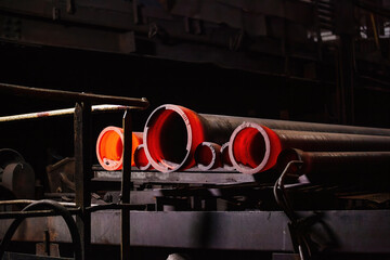 Freshly cast red hot iron pipe at the foundry