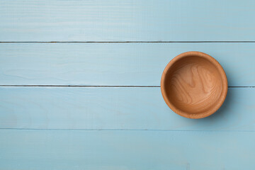 Wooden bowl on wooden background, top view