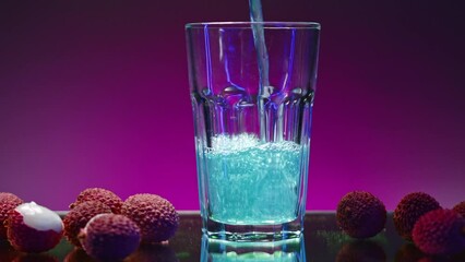 Blue drink is poured into glass on isolated background. Stock clip. Carbonated blue drink is poured into clear glass in bar. Bright drink with ingredients and fruits around