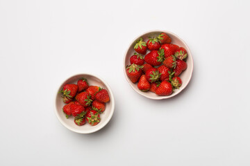 Bowls with fresh strawberries on color background, top view