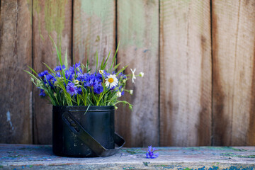 Bright blue bouquet of cornflowers and chamomile in a decorative old bowler hat on the background...