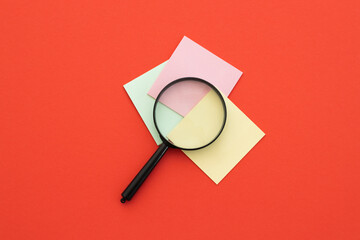Magnifying glass and sticky notes on red. Search concept