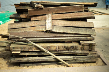 Old boards stand in heap. Broken planks lie on beach.