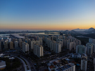 Fototapeta na wymiar Aerial view of Jacarépagua lagoon in Rio de Janeiro, Brazil. Residential buildings and mountains around the lake. Barra da Tijuca beach in the background. Sunny day. Sunset. Drone photo