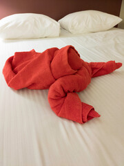 Obraz na płótnie Canvas Red lobster shaped towel on the bed