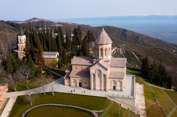 Scenic spring aerial view of Church of St. Nino in monastic complex of Bodbe nunnery on hillside overlooking Alazani Valley and Greater Caucasus mountains in background, Sighnaghi, Kakheti, Georgia