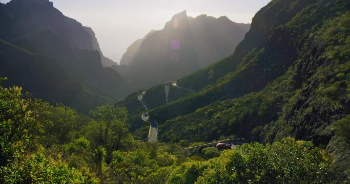 Winding road at sunset in Masca Gorge and Masca Valley Park. Tenerife, Canary Islands, Spain. Rental car. Beautiful view of the mountain range and the rays of the setting sun.