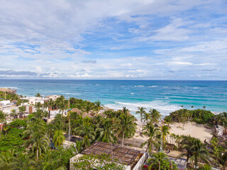 View of coastal area with wavy blue Caribbean Sea on a cloudy day in Tulum beach