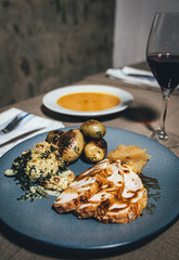 Thanksgiving dinner with turkey, potatoes and pumpkin soup served in blue and white plate with a glass of wine in deluxe restaurant