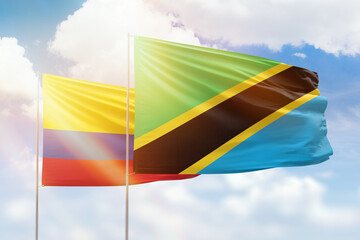 Sunny blue sky and flags of tanzania and colombia