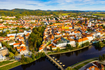 Autumn landscape with Old Town of Czech city of Pisek on banks of Otava river on sunny day..