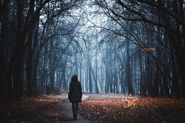 Girl on the road in a mysterious forest. Background wallpaper. Strange forest. Mystic atmosphere. Dark scary road. Paranormal another world. Ghost in the fog. The pursuit. Horrible dream.