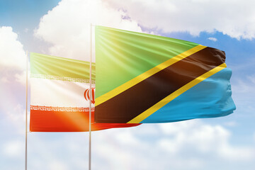 Sunny blue sky and flags of tanzania and iran