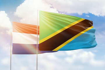 Sunny blue sky and flags of tanzania and netherlands