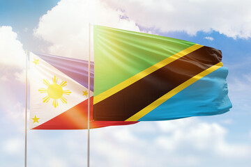 Sunny blue sky and flags of tanzania and philippines