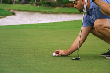 a golfer lining up is golf ball to putt